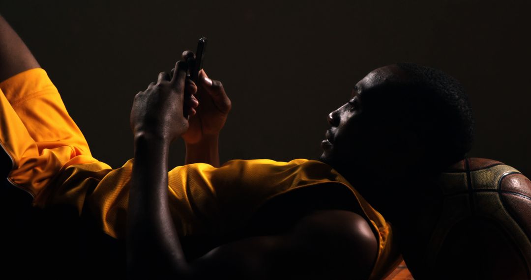 Basketball Player Relaxing Using Smartphone on Court