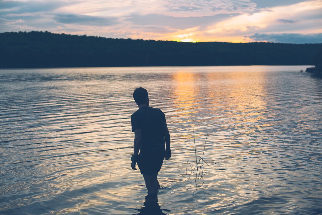 Silhouette of Person Walking in Tranquil Lake at Sunset - Free Images, Stock Photos and Pictures on Pikwizard.com