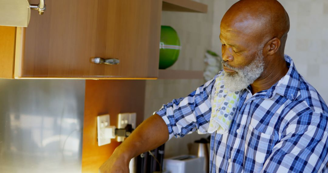 Senior Man Cooking in Kitchen with Spotted Towel Over Shoulder - Free Images, Stock Photos and Pictures on Pikwizard.com