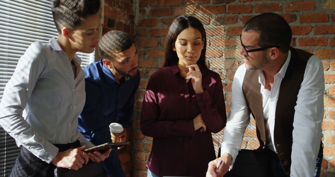 Diverse Team Collaborating on Project in Modern Brick Office