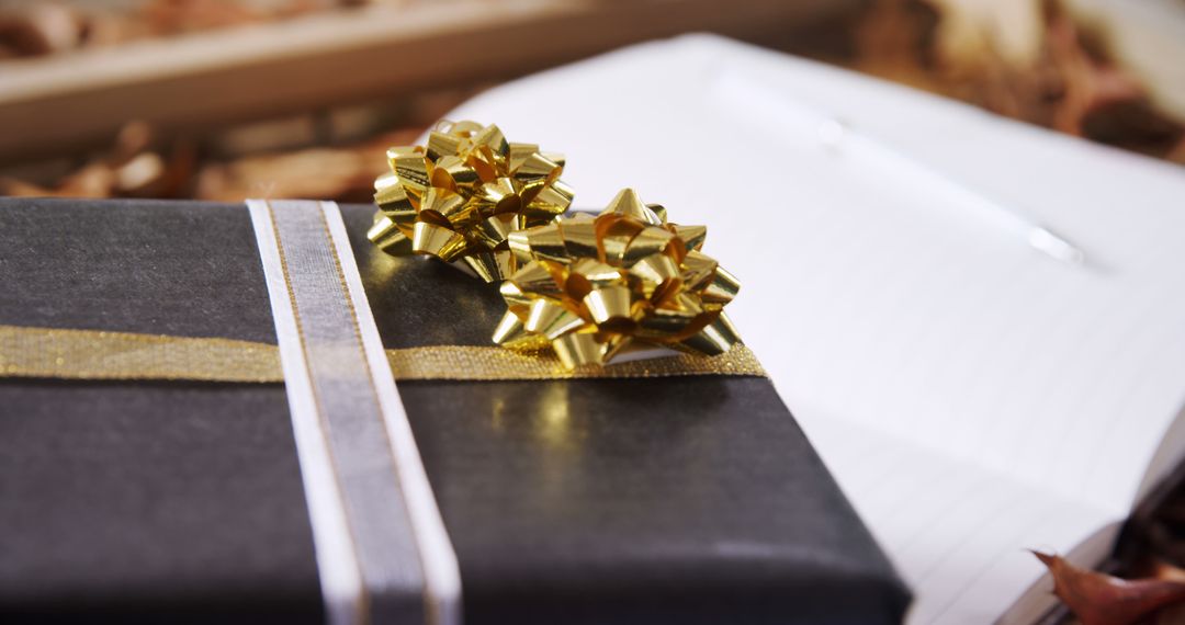 Elegant Black Gift Box with Golden Bows on Pergament Notebook - Free Images, Stock Photos and Pictures on Pikwizard.com