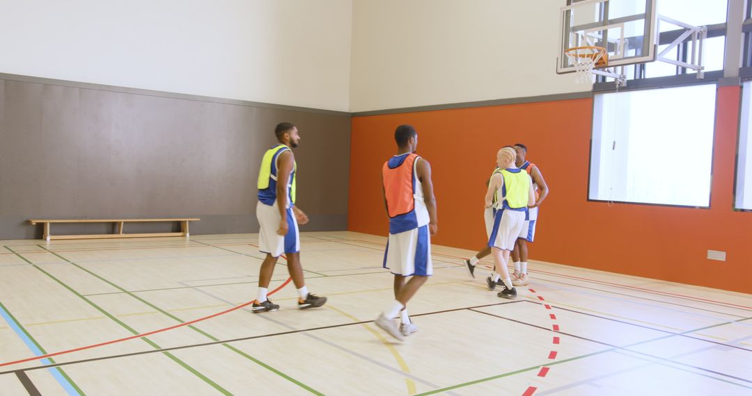 Basketball Team Practicing on Indoor Court with Uniforms and Pinnies