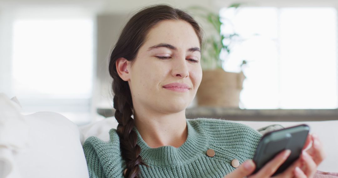 Young Woman Smiling while Using Smartphone on Couch at Home - Free Images, Stock Photos and Pictures on Pikwizard.com