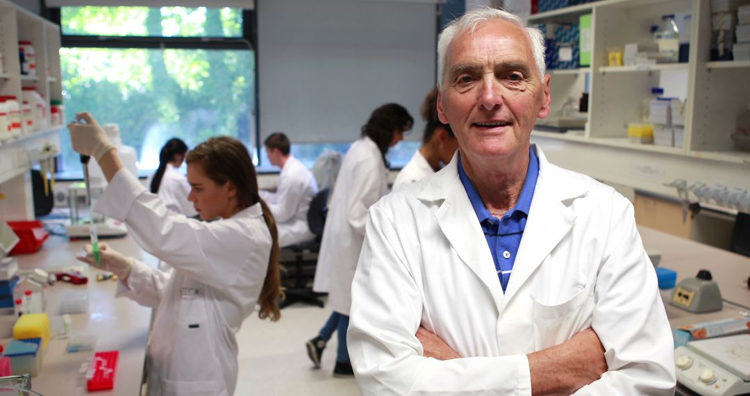 Senior Scientist Smiling in Laboratory with Team Working in Background - Free Images, Stock Photos and Pictures on Pikwizard.com