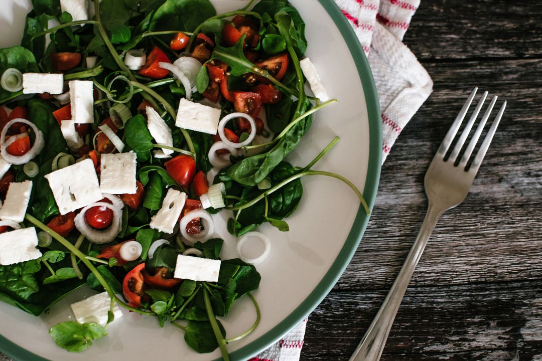 Fresh spinach salad with feta, cherry tomatoes and spring onions on rustic wood