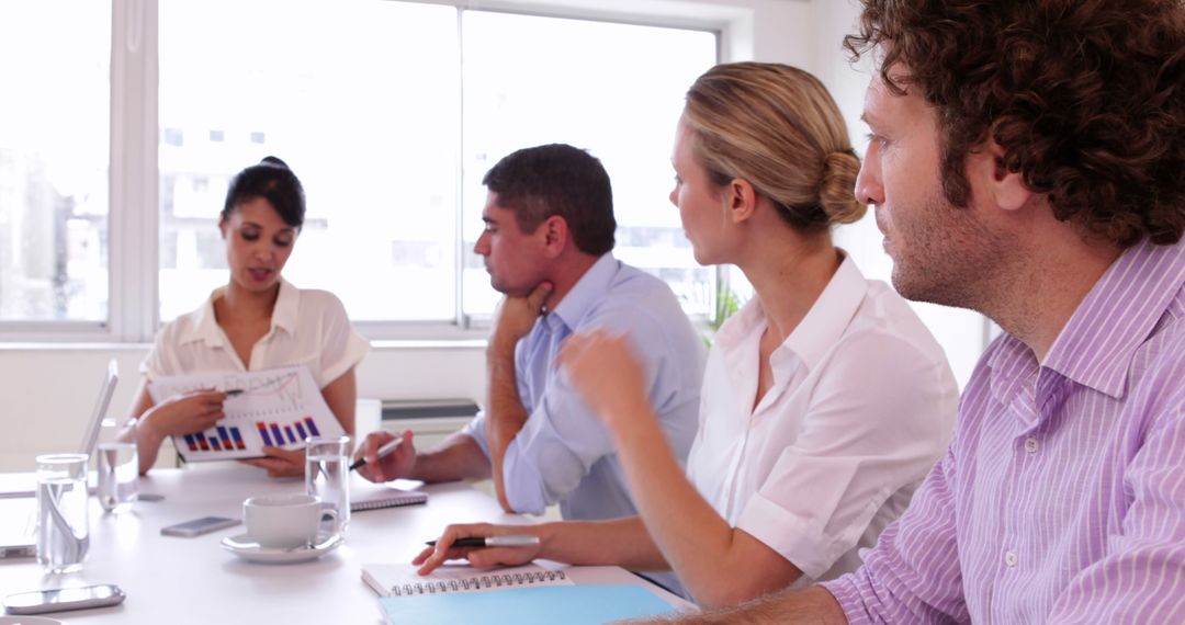 Team Discussing Business Report During Meeting in Modern Office - Free Images, Stock Photos and Pictures on Pikwizard.com