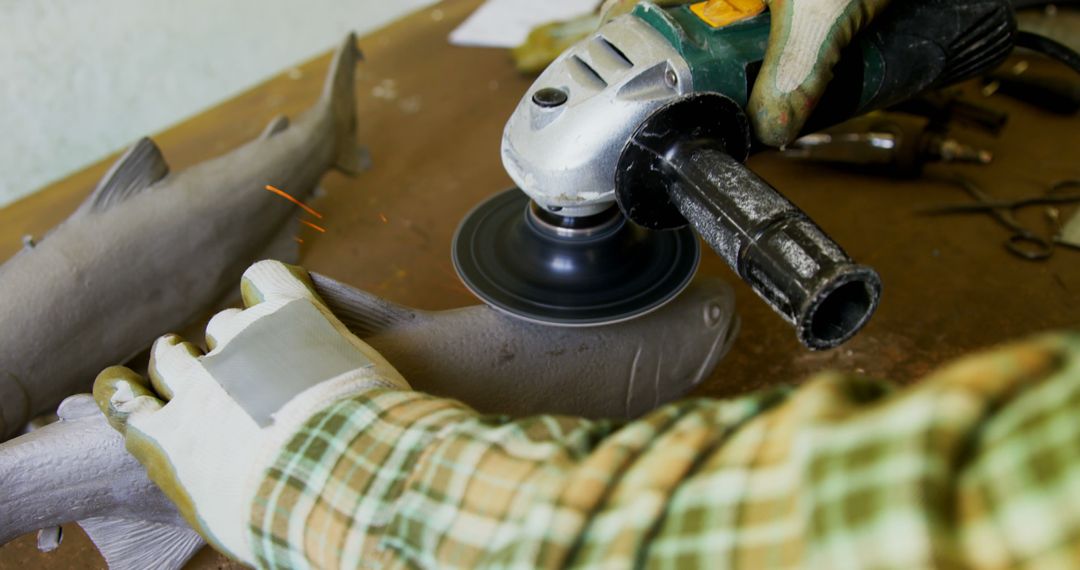 Person Using Angle Grinder on Wooden Fish Carving