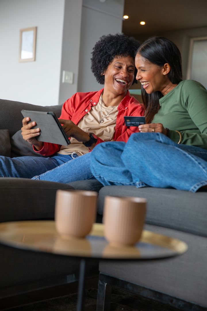 Joyful Friends Browsing on Tablet at Home with Credit Card