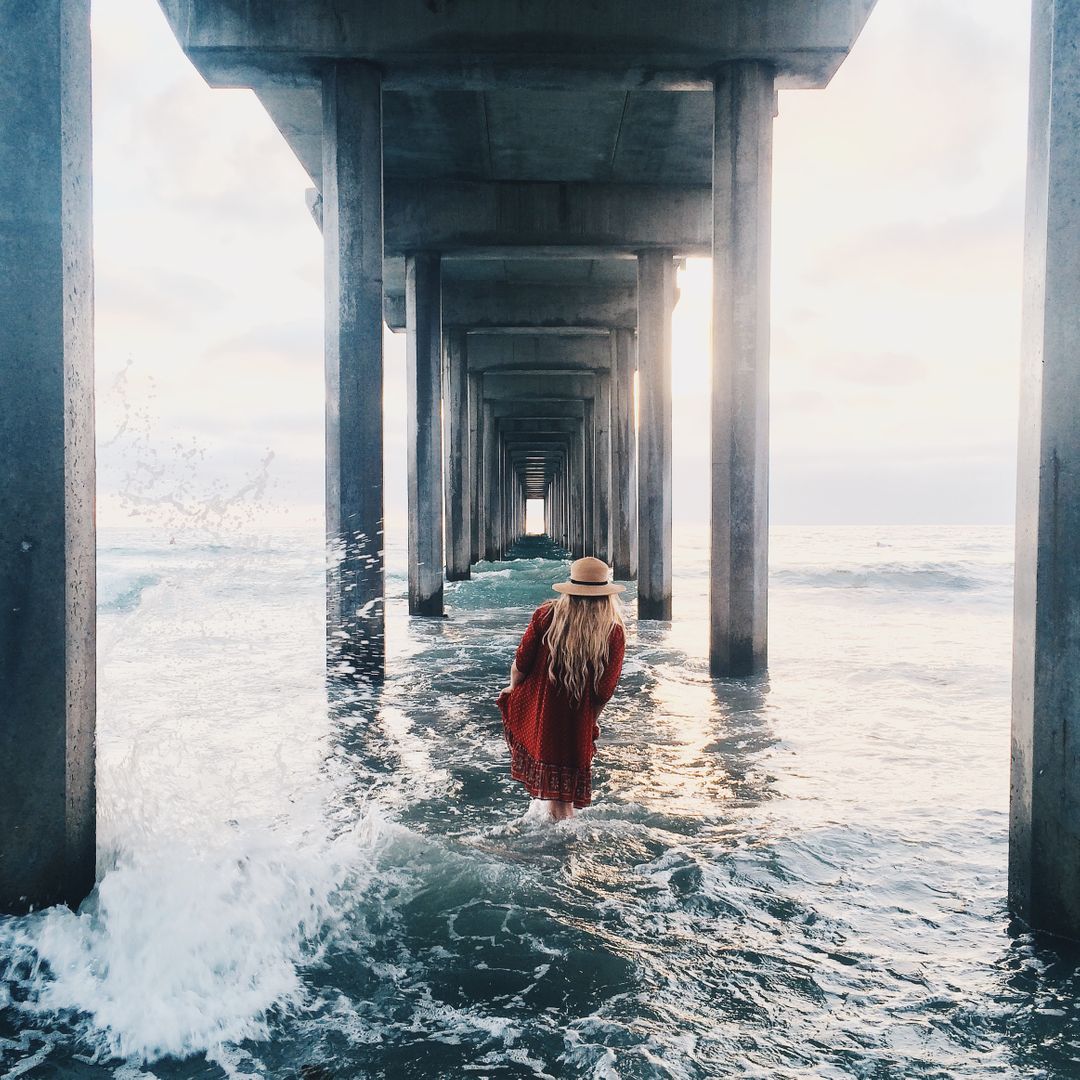 Woman Walking Under a Pier at Sunset - Free Images, Stock Photos and Pictures on Pikwizard.com