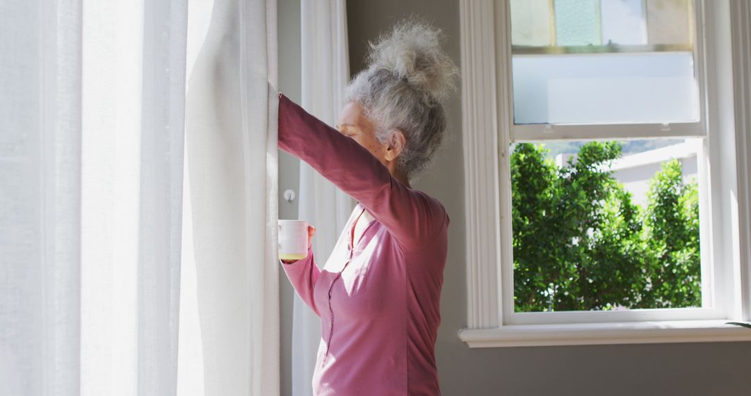 Elderly Woman Opening Curtains with Coffee on Quiet Morning - Free Images, Stock Photos and Pictures on Pikwizard.com