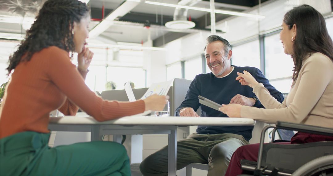 Diverse Team Collaborating Around Table with Wheelchair in Bright Open-Plan Office