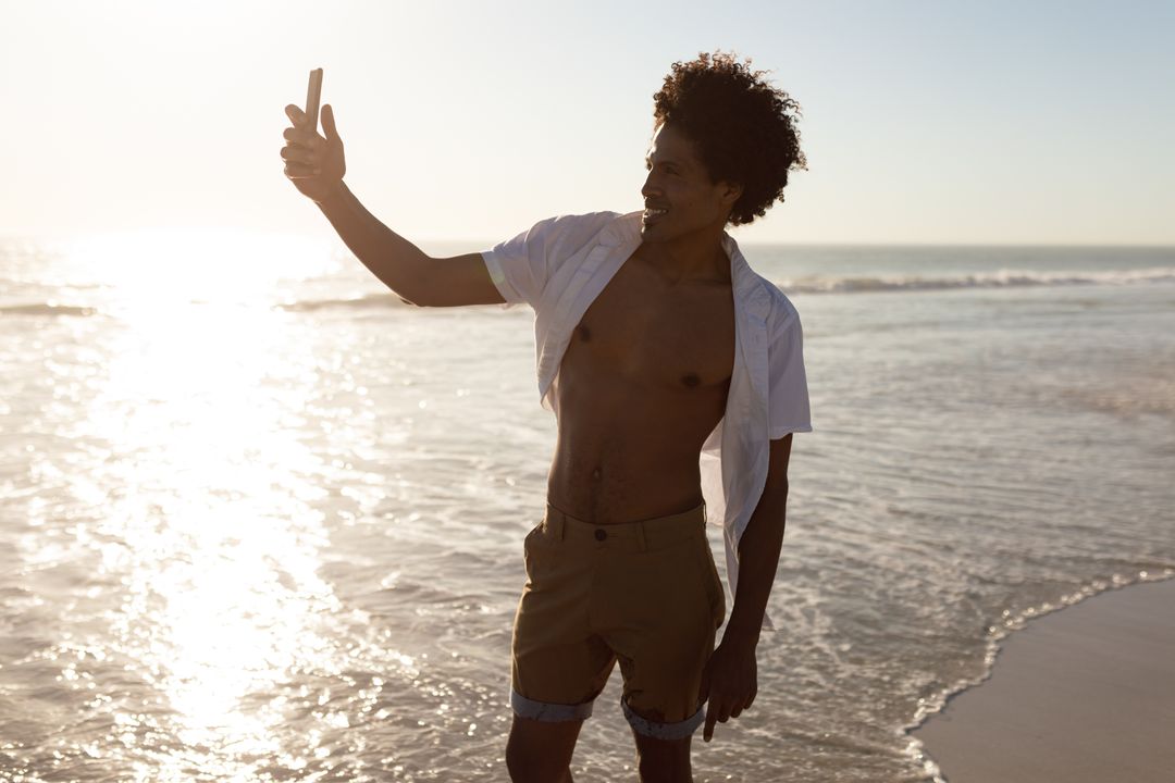 Young Man Taking Selfie on Beach at Sunset - Free Images, Stock Photos and Pictures on Pikwizard.com