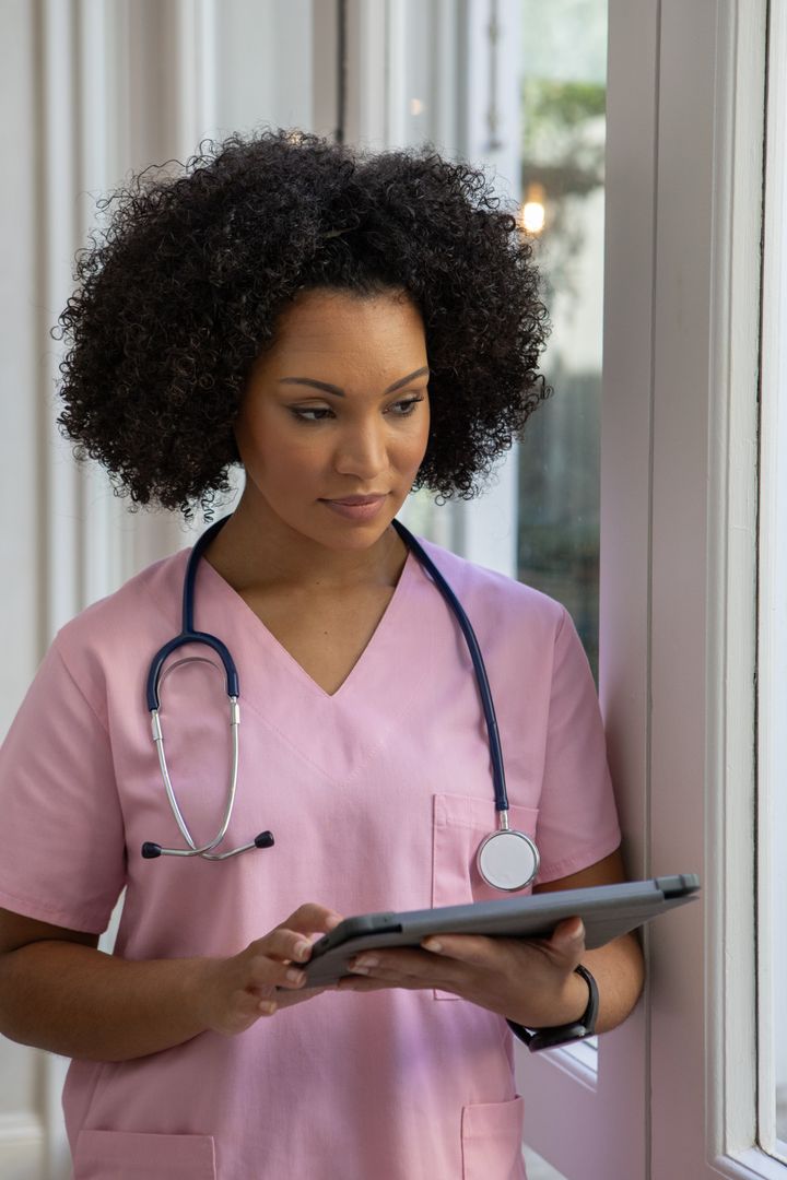 Nurse Using Tablet Technology in Hospital Corridor