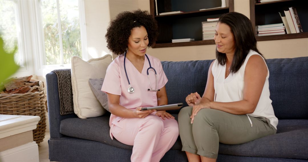 Nurse in Pink Scrubs Discussing Health with Patient on Couch