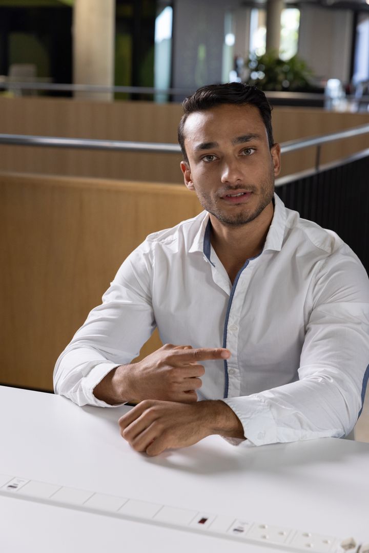 Professional Man Pointing to Forearm in Modern Office Setting