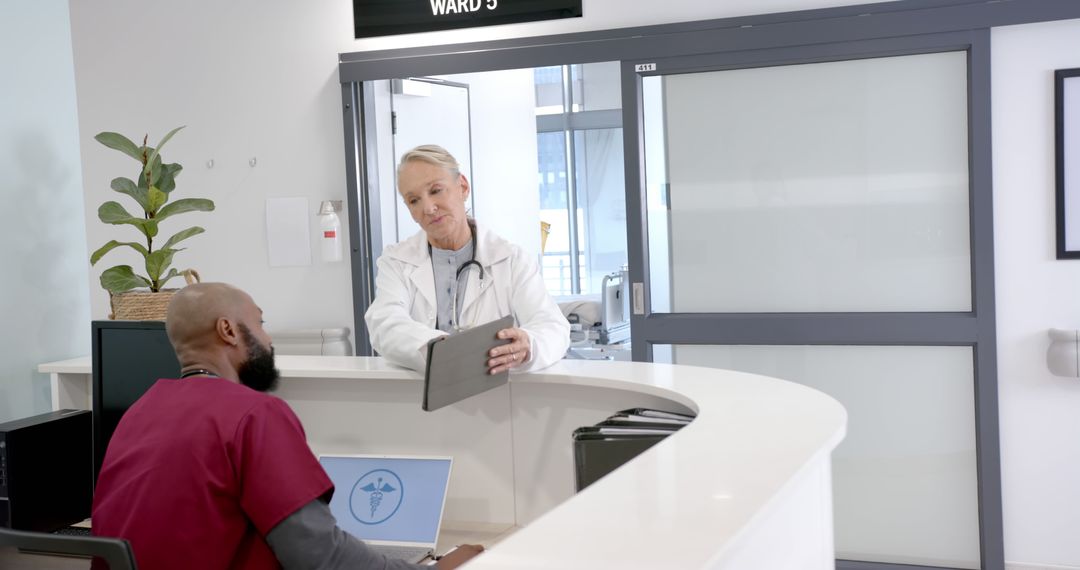 Medical Receptionist and Doctor Discussing Patient Records at Hospital Desk - Free Images, Stock Photos and Pictures on Pikwizard.com