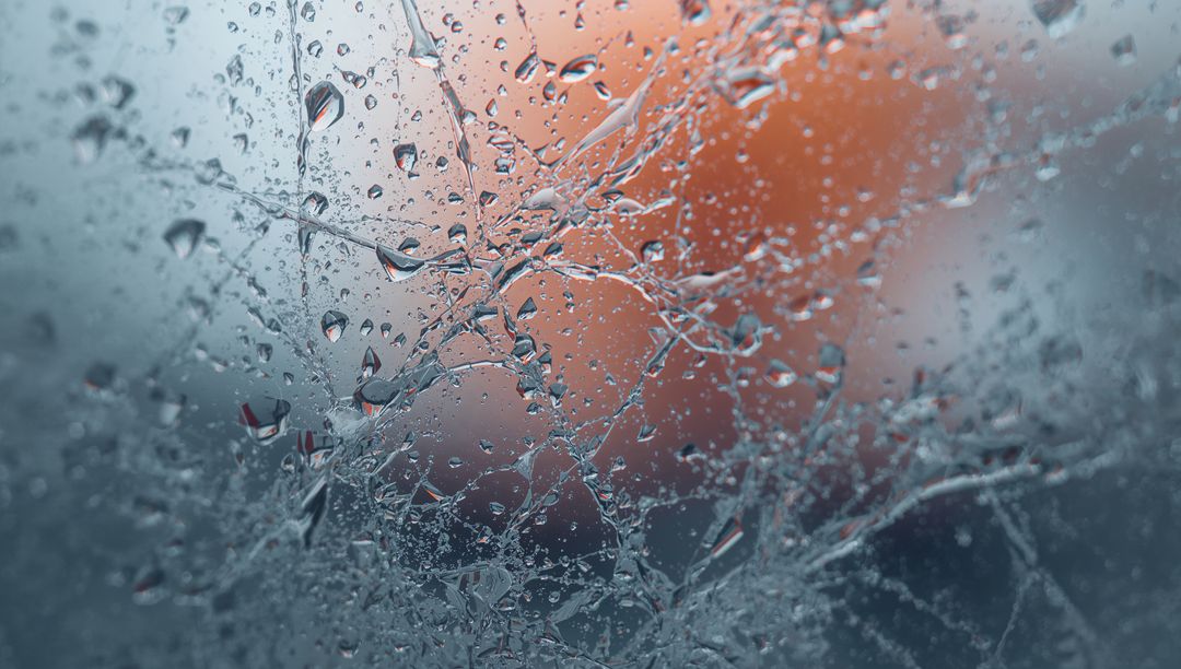 Wet glass catching light through frosted pane, water droplets and colorful bokeh closeup