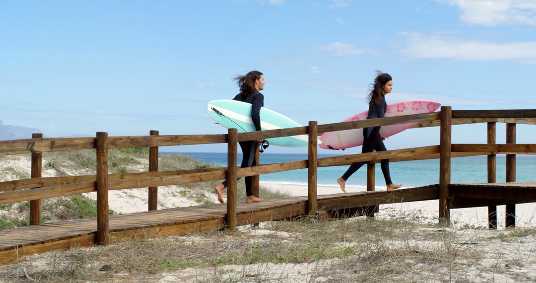Two young women head to the beach for a surfing day. - Free Images, Stock Photos and Pictures on Pikwizard.com