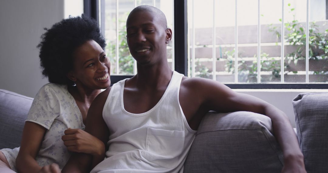 Joyful African American Couple Relaxing on Couch in Morning Light
