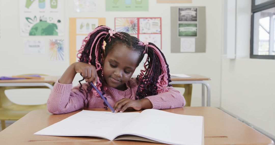 African American Girl Writing in Classroom with Concentration and Creativity