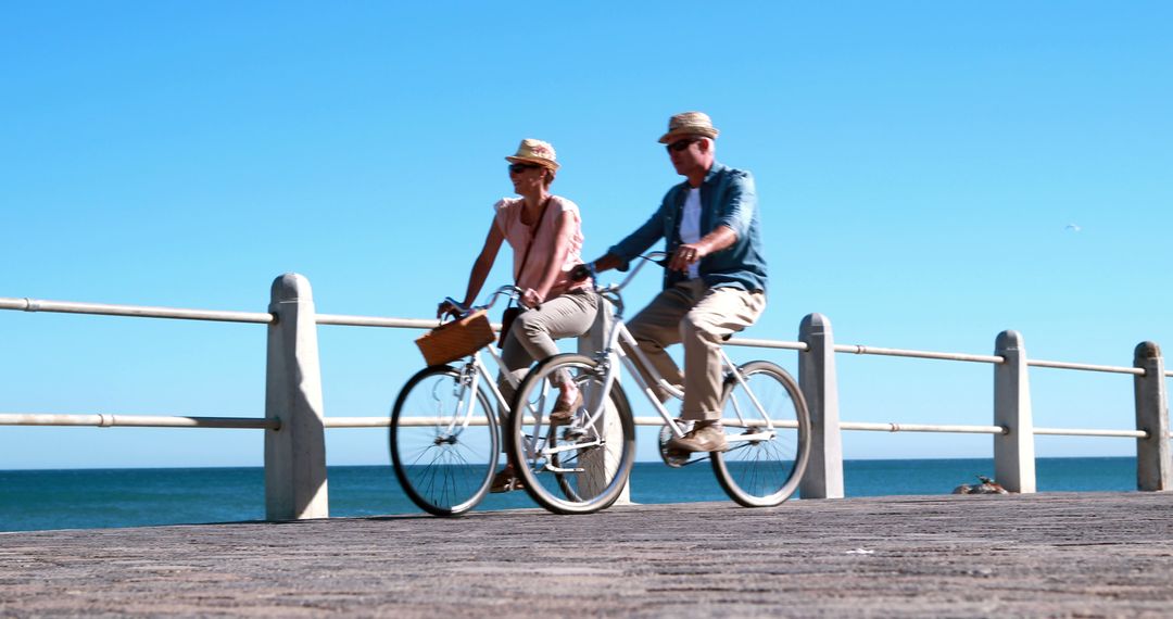 Couple Cycling On Boardwalk By The Ocean - Free Images, Stock Photos and Pictures on Pikwizard.com