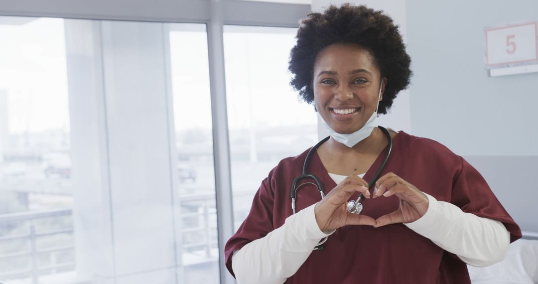 Smiling African American Nurse Making Heart Gesture in Hospital - Free Images, Stock Photos and Pictures on Pikwizard.com