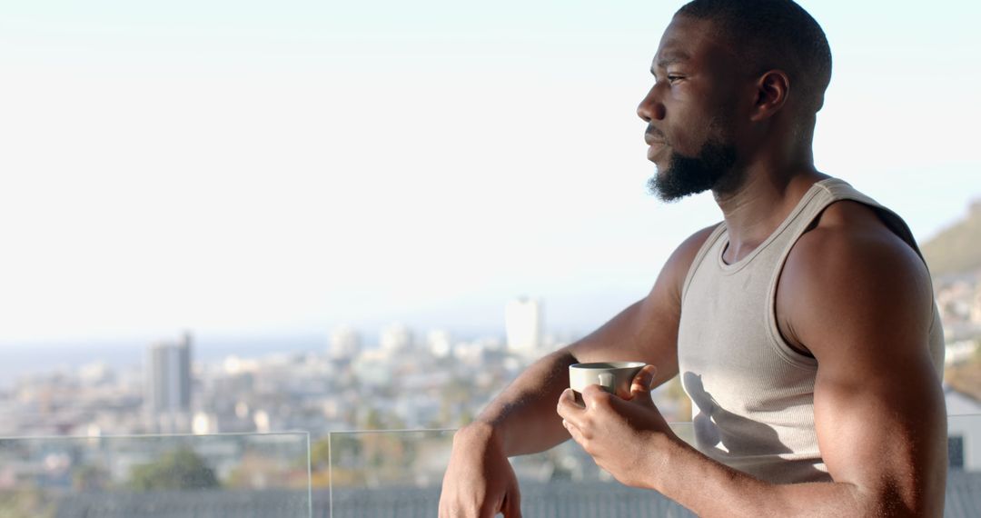 Contemplative Man Holding Mug on Balcony with Urban View