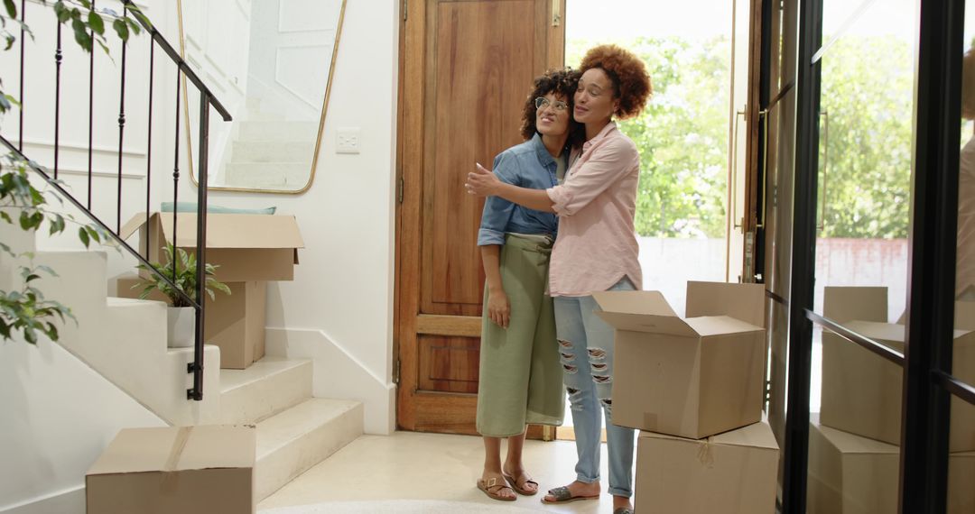 Couple moving into new home embracing in sunlit entryway with moving boxes
