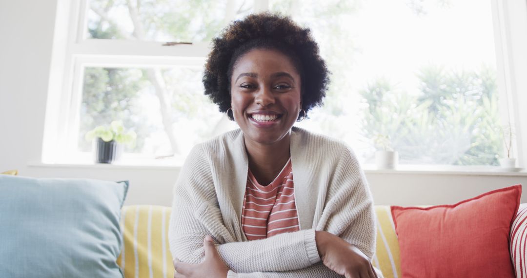 Smiling African American Woman Relaxing at Home on Colorful Sofa - Free Images, Stock Photos and Pictures on Pikwizard.com