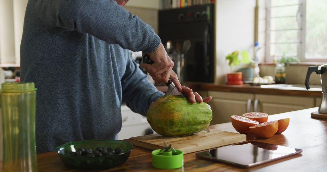 Senior Man Slicing Papaya in Kitchen With Fresh Fruit and Culinary Tools - Free Images, Stock Photos and Pictures on Pikwizard.com