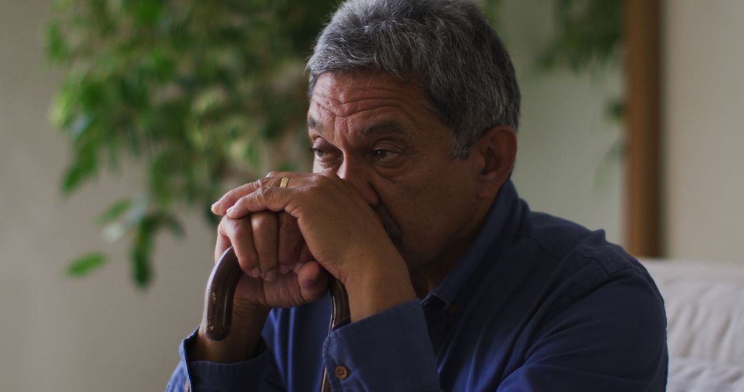 Elderly Man Deep in Thought Holding Cane by Indoor Plants - Free Images, Stock Photos and Pictures on Pikwizard.com