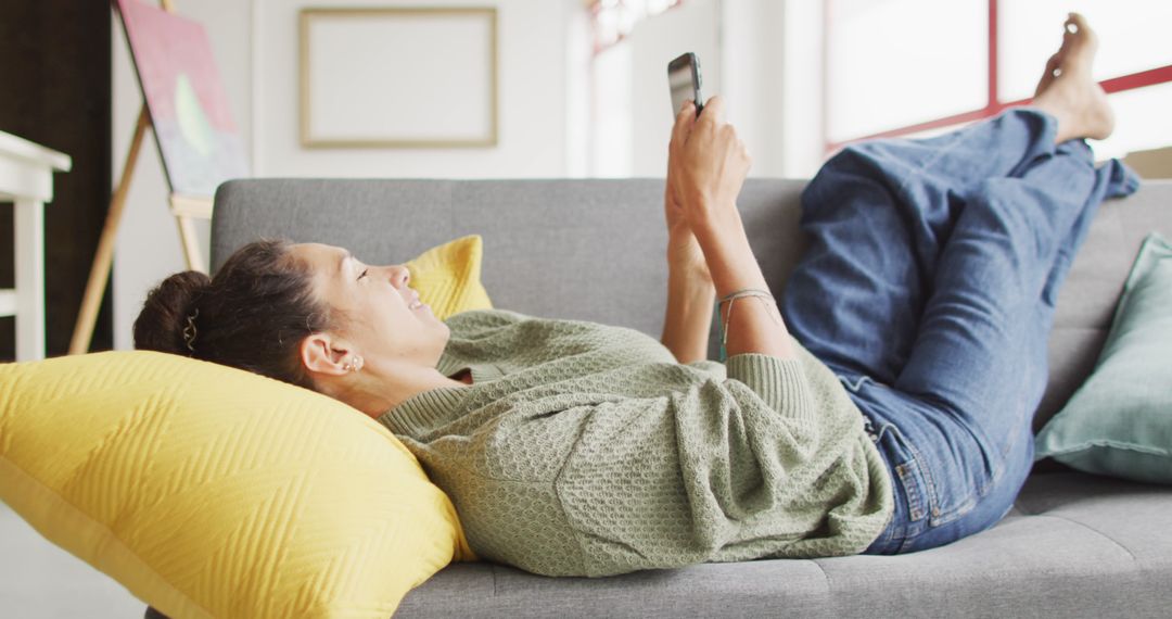 Relaxed woman scrolling on smartphone while laying on couch - Free Images, Stock Photos and Pictures on Pikwizard.com