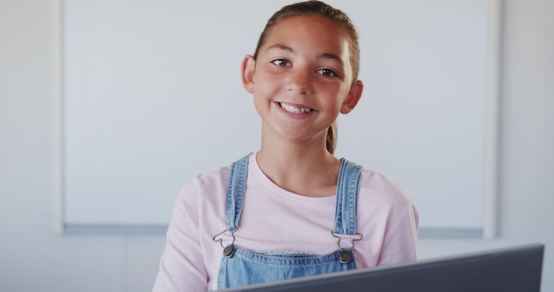 Smiling Student in Classroom Wearing Denim Overalls