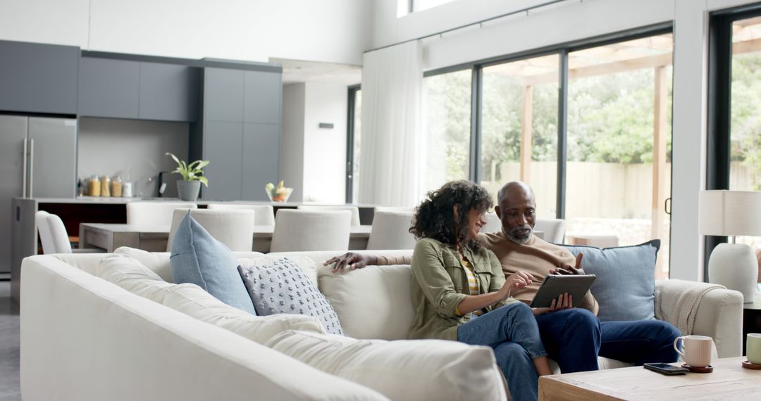 Ethnically Diverse Couple Using Digital Tablet in Modern Living Room - Free Images, Stock Photos and Pictures on Pikwizard.com