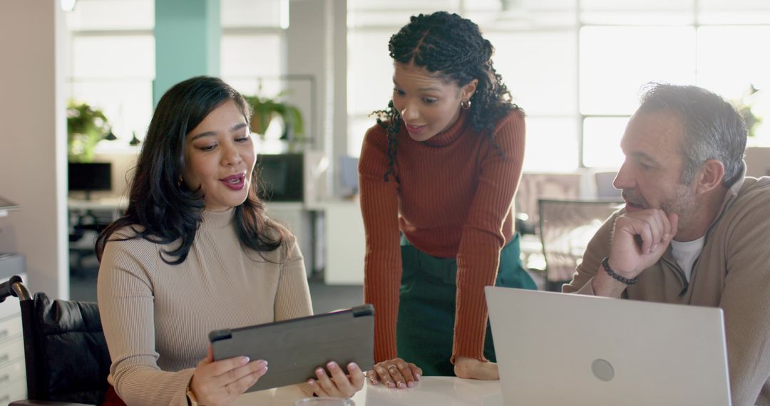 Diverse team collaborating over tablet in modern open-plan office