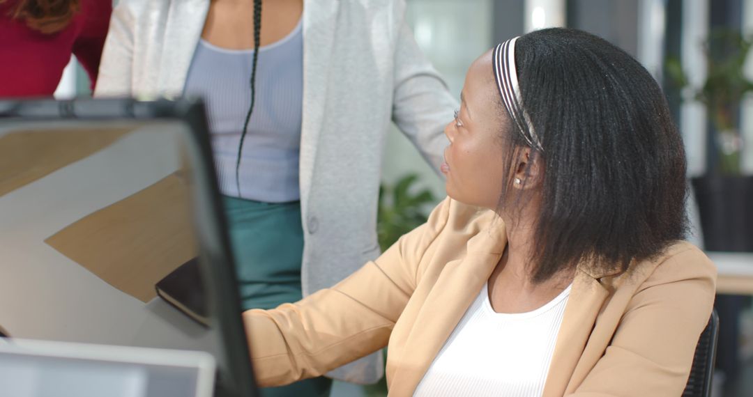 Black professional collaborating with diverse coworkers at modern office desk with monitor