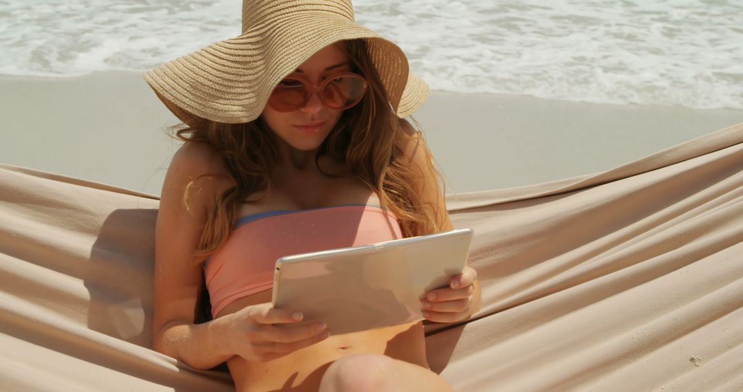 Woman Relaxing in Hammock on Beach with Digital Tablet