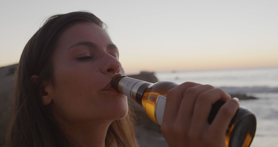 Young Woman Drinking Beer at Beach During Sunset - Free Images, Stock Photos and Pictures on Pikwizard.com