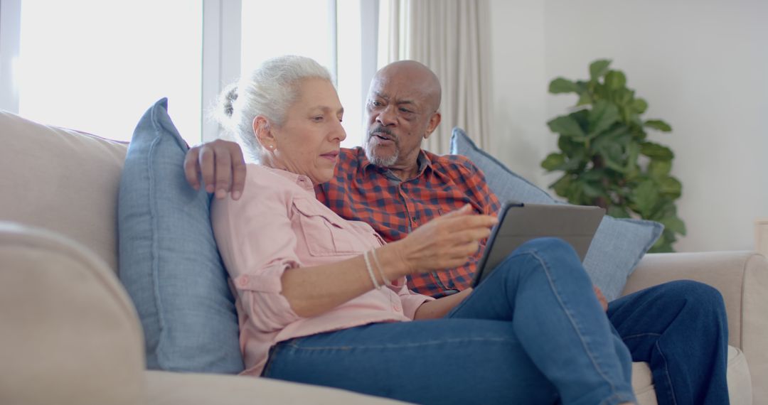 Senior Couple Sitting on Couch Using Tablet Together - Free Images, Stock Photos and Pictures on Pikwizard.com