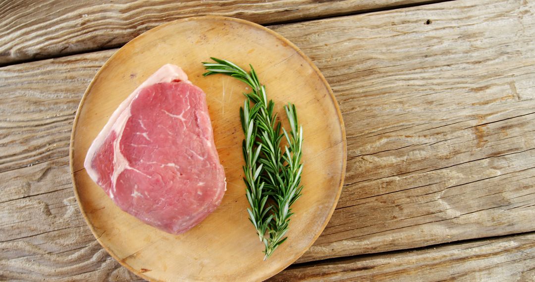 Raw pork chop with fresh rosemary on wooden plate - Free Images, Stock Photos and Pictures on Pikwizard.com