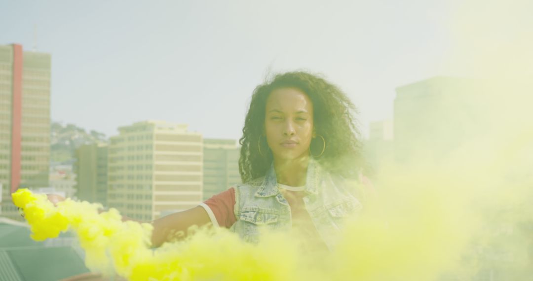 Confident Woman Waving Yellow Smoke Flare on Urban Rooftop - Free Images, Stock Photos and Pictures on Pikwizard.com