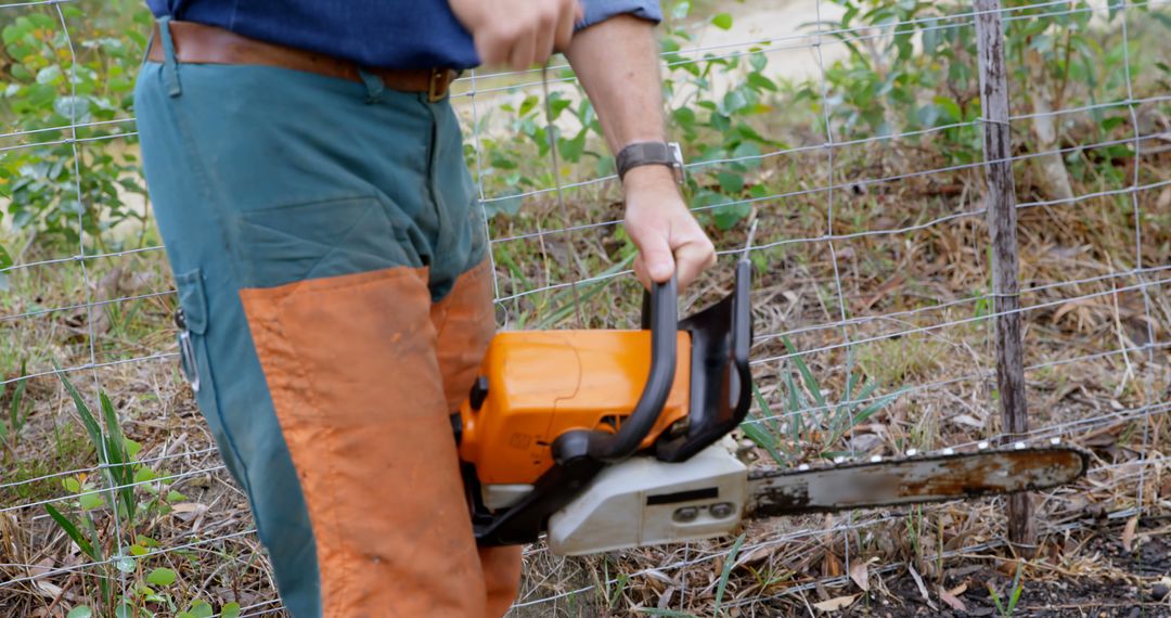 Man Holding Chainsaw in Outdoor Woodland Area with Fencing - Free Images, Stock Photos and Pictures on Pikwizard.com