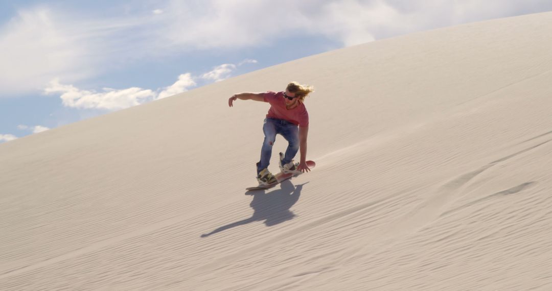 Adventurous Sandboarding Down Desert Dune with Clear Sky