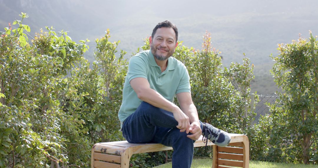 Man Tying Shoelaces on Wooden Bench in Tranquil Garden Setting