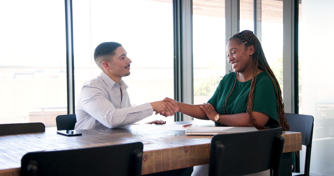 Business Colleagues Handshaking Across Table in Modern Office