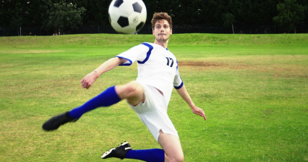 A young Caucasian male athlete is in action, kicking a soccer ball during a game, with copy space - Free Images, Stock Photos and Pictures on Pikwizard.com