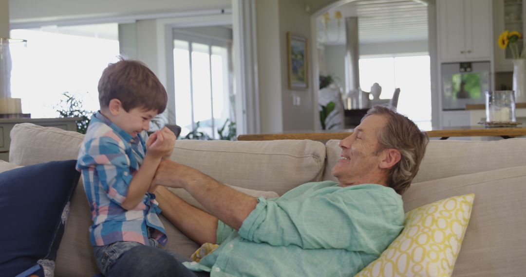 Grandfather and Grandson Laughing Together on Sofa - Free Images, Stock Photos and Pictures on Pikwizard.com