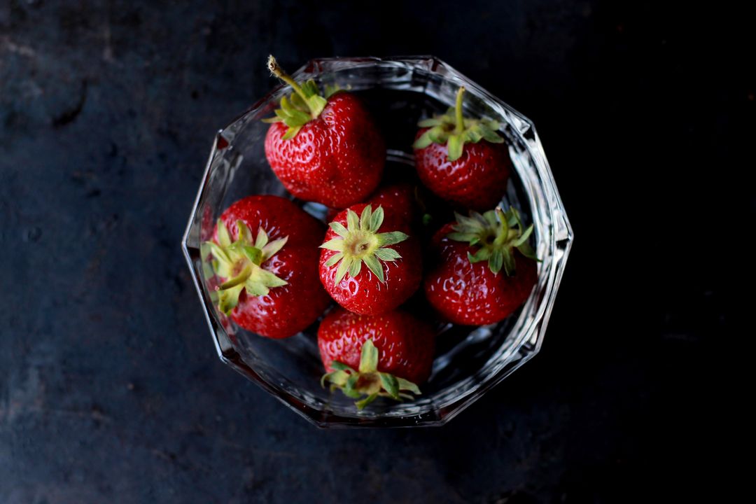 Ripe Strawberries in Faceted Glass Bowl on Dark Rustic Surface, Top View
