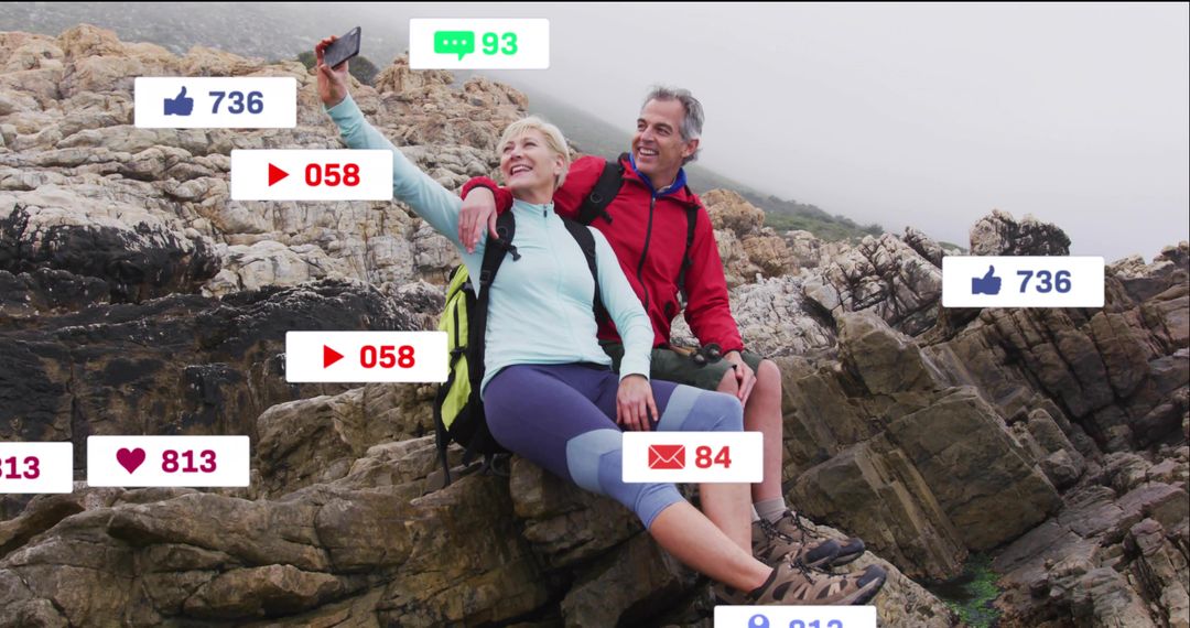 Mature couple posing on coastal rocks taking selfie with social media reaction overlays