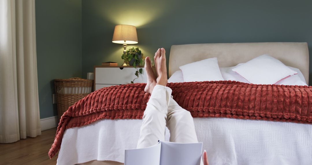 Relaxed Woman Reading Book in Cozy Bedroom with Rust Red Bedding and Ambient Lighting